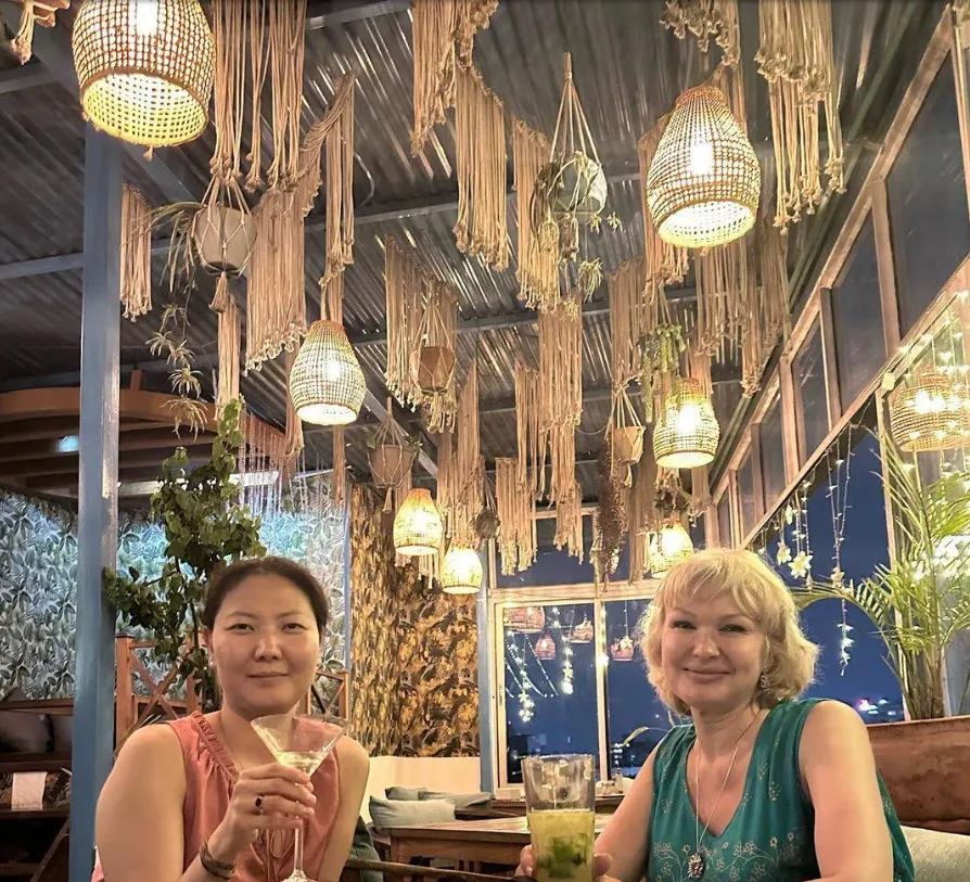 Two guests enjoying cocktails beneath macramé lanterns on the rooftop