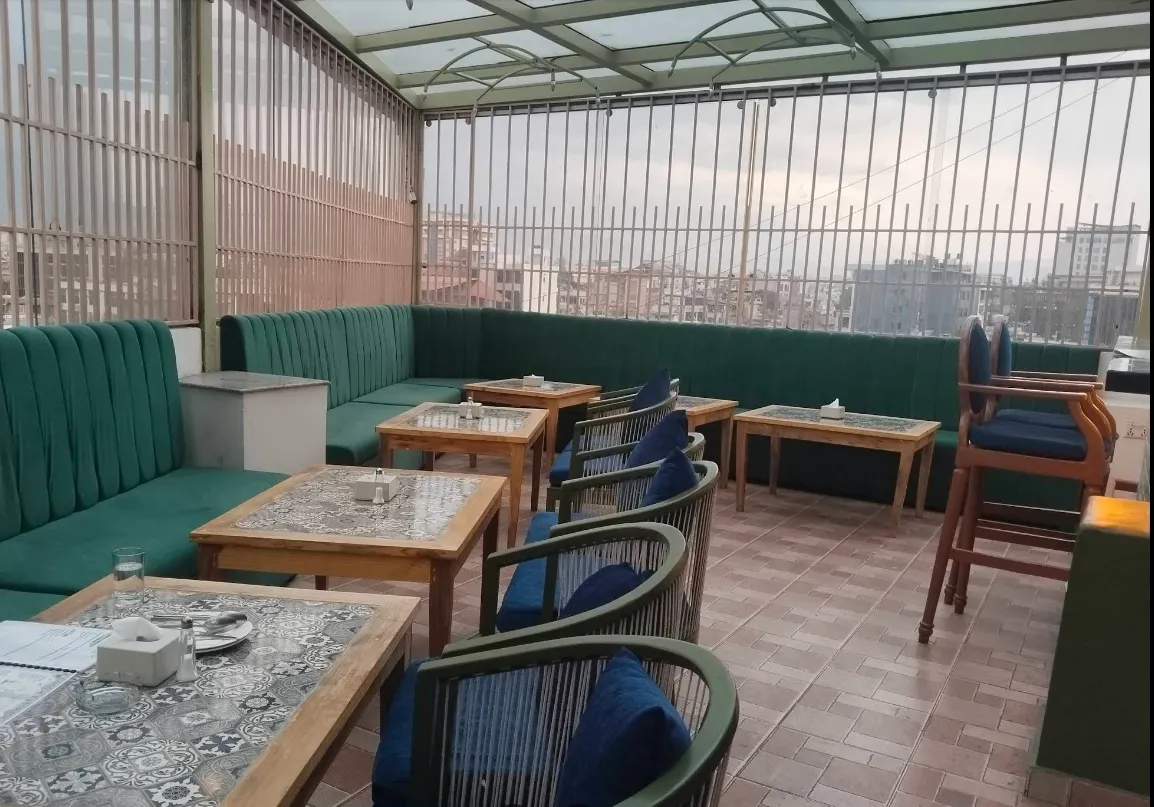 Green velvet booths and tiled tables along the glass-walled rooftop terrace