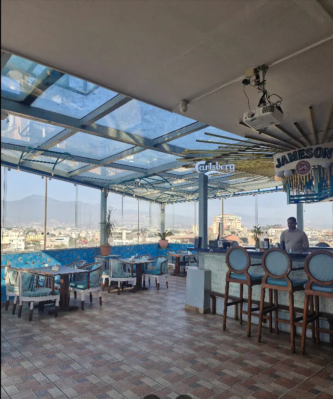 Daytime rooftop terrace with a glass canopy and panoramic Kathmandu valley views