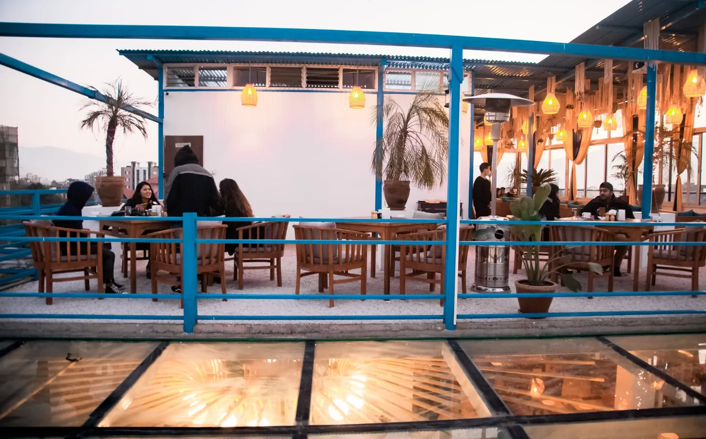 Copacabana rooftop terrace with blue railings and palms glowing at golden hour over Kathmandu