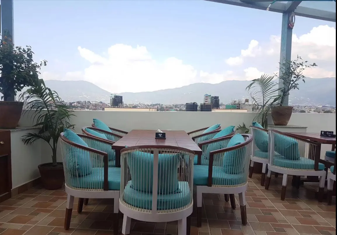 Teal rooftop armchairs facing the hills and skyline of the Kathmandu valley